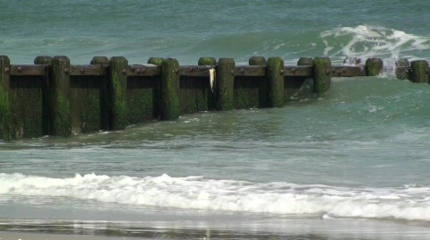 Waves Crashing Onto The Pier At The Beach