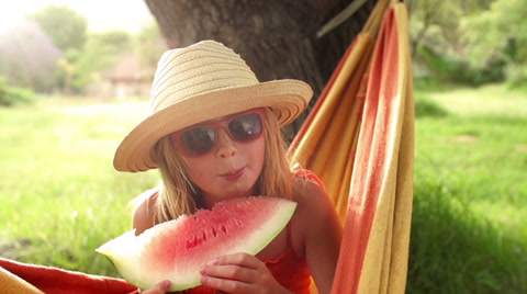 Girl In Hammock Holding Fresh Watermelon Slice
