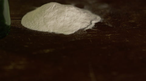 A Stack Of Hundreds Falls In Front Of A Pile Of Cocaine