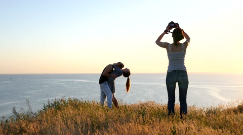 Woman Make Photo Of Couple Tenderly Kissing Over A Precipice In Golden Sunset