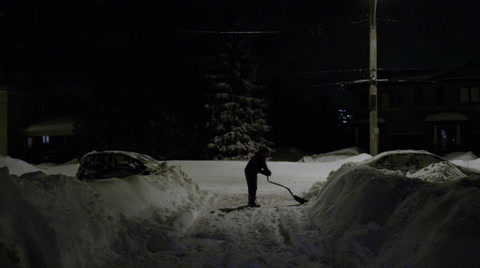 Man Shovelling Driveway At Night After A Blizzard