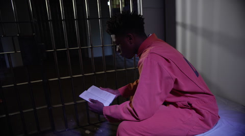 Tilt Down To Reveal Inmate Studying And Reading In Prison