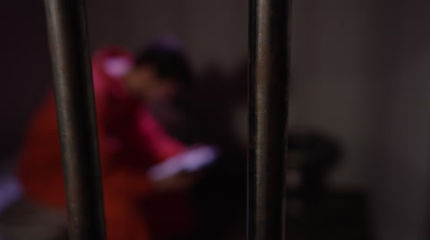Tilt Down To Man Reading In Jail Cell